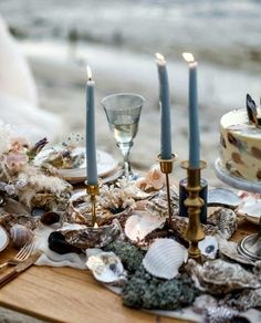 a table topped with lots of different types of food and candles on top of it