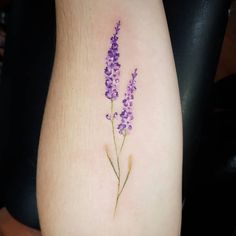 a small tattoo with purple flowers on the side of a woman's leg,