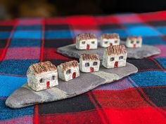 some little houses are sitting on top of a table cloth with red and blue plaid