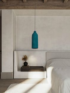 a bed sitting under a blue light next to a white wall and wooden beams on the ceiling