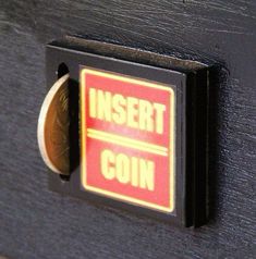 a close up of a coin slot on a black cabinet with an insert for coins