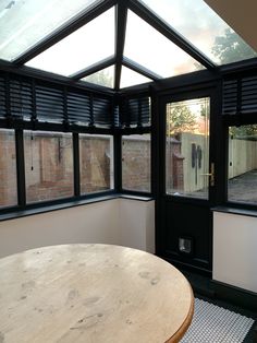 an enclosed patio area with a wooden table and black shutters