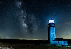 a light house sitting on top of a lush green field under a night sky filled with stars