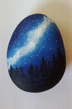 a painted rock sitting on top of a white table next to a painting of the night sky