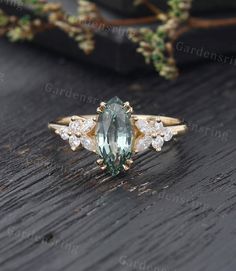 an aqua and white diamond ring on top of a wooden table with greenery in the background