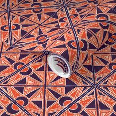 an orange and blue wallpaper with geometric designs on the floor next to a roll of tape