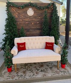 a white couch sitting in front of a wooden wall decorated with christmas trees and lights