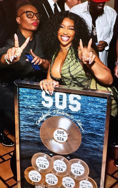 some people are posing for a photo with an award in front of them and one woman is giving the peace sign