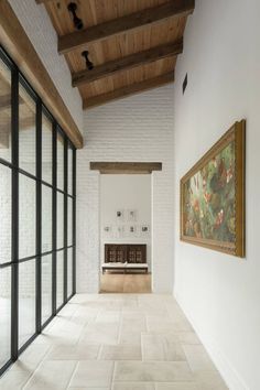 an empty room with large windows and a painting hanging on the wall next to it