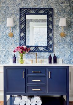 a bathroom vanity with blue cabinets and gold handles, two white towels on the counter