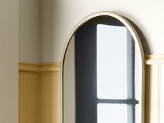 an arched window in the corner of a white room with yellow trim on the walls