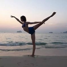 a woman doing yoga on the beach with her leg in the air and arms out