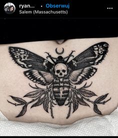 a woman's stomach with a black and white moth tattoo on the side of her belly