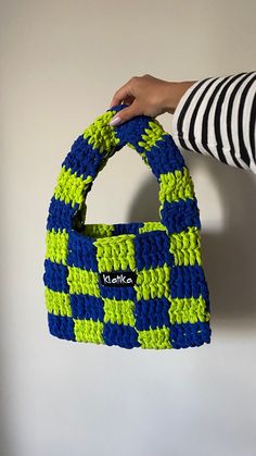 a hand holding a blue and green purse