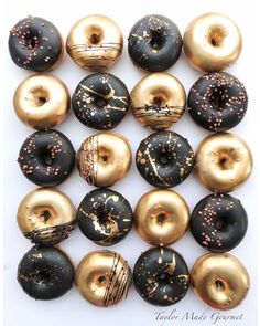 there are many donuts that have gold sprinkles on them and black frosting