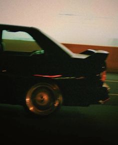 a black car driving down a street next to a tall building