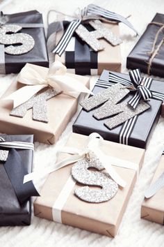 many presents wrapped in black and white paper with silver glitter numbers on them are sitting on a blanket