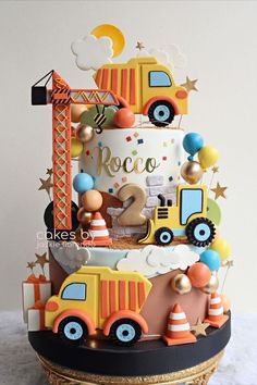 a three tiered cake decorated with construction vehicles and stars on it's sides