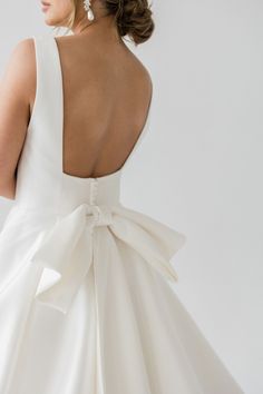 a woman in a white dress with a big bow on her back