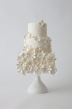 a three tiered white wedding cake with flowers on it's top and bottom