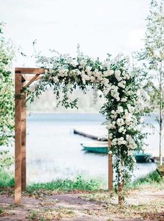 an outdoor wedding ceremony with white flowers and greenery on the altar by the water