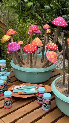 there are many colorful mushrooms in the potted planters on the wooden table outside