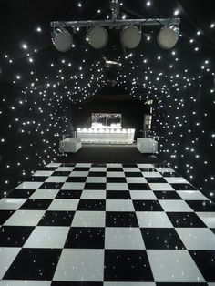 a black and white checkered dance floor with lights on it's sides in front of a stage