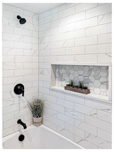 a white tiled bathroom with black fixtures and plants in the window sill above the bathtub