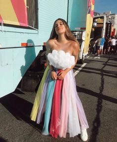 a woman standing in front of a trailer wearing a rainbow colored dress and white sneakers