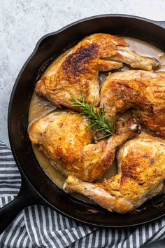 roasted chicken in a skillet with gravy and fresh rosemary garnish