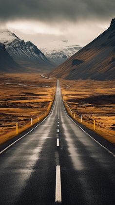 an empty road in the middle of nowhere, with mountains in the backgroud