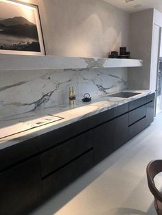 a modern kitchen with marble counter tops and black cabinetry, along with a dining room table