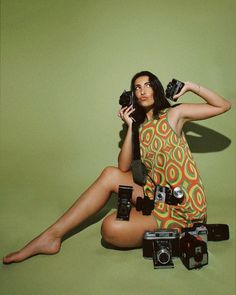 a woman sitting on the ground holding two cameras