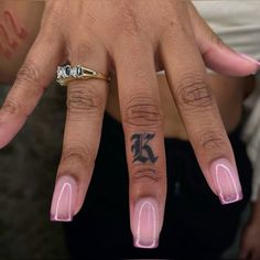 a woman's hand with pink nail polish and tattoos on her left ring finger