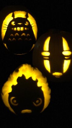 three pumpkins with faces carved into them in the shape of cats and dogs, all lit up at night