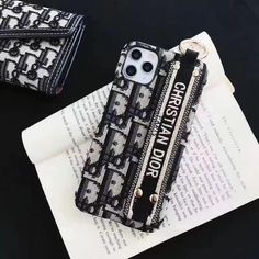 a black and white phone case sitting on top of an open book next to a wallet