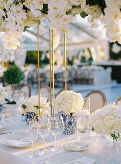 the table is set with white flowers and place settings for guests to sit down at