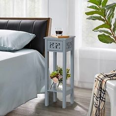 a bed room with a neatly made bed and a plant on the nightstand next to it