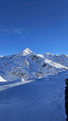 a man standing on top of a snow covered ski slope next to a mountain range