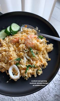 a black plate topped with rice and veggies on top of a white table