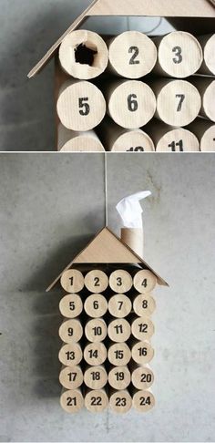 a house made out of toilet paper with numbers on the front and sides, hanging from a thread spool