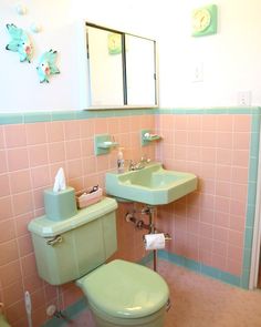 a green toilet sitting next to a pink sink in a room with pink tiles on the walls