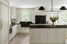 a large kitchen with white cabinets and black counter tops, along with an island in the middle