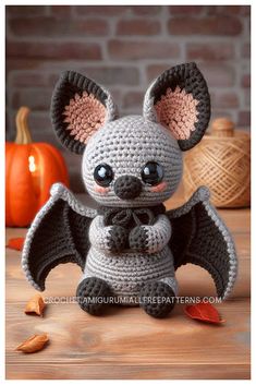 a crocheted bat sitting on top of a wooden table next to pumpkins