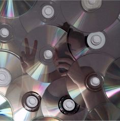 many cds are stacked on top of each other with one person's hand in the middle