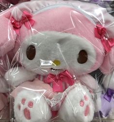 a hello kitty stuffed animal in a plastic bag with pink bows on its head and feet