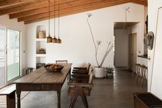 a wooden table sitting in the middle of a room next to an open door and windows