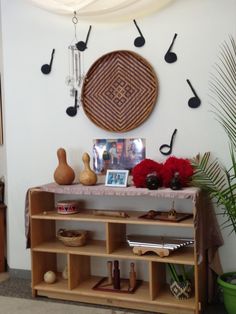 a shelf with musical instruments and vases on it in front of a wall decoration