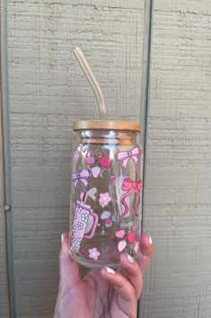 a hand holding a glass with a straw in it and pink flowers on the inside