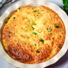 a cheesy casserole in a white dish with parsley on top